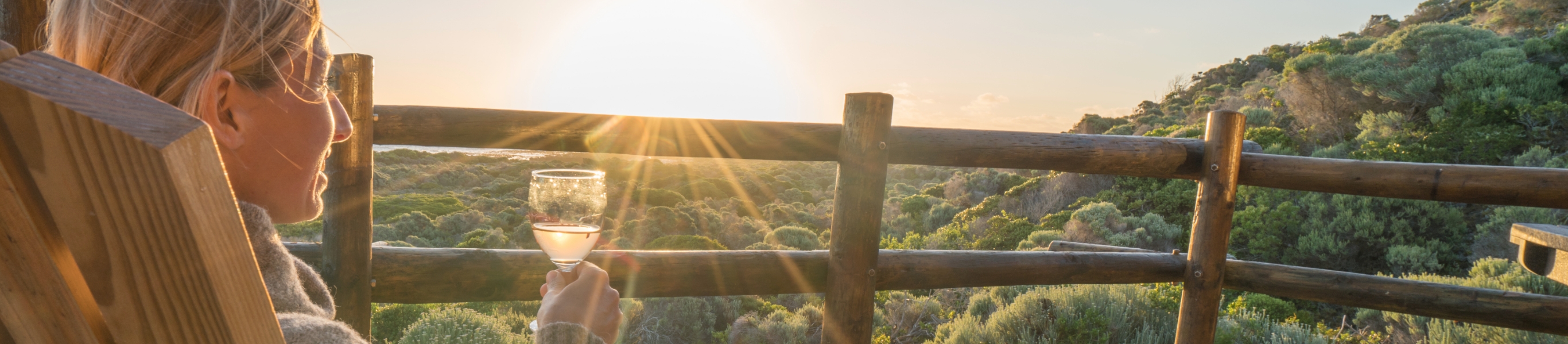 Frau genießt Rosé-Wein am Sonnenuntergang auf der Terrasse.