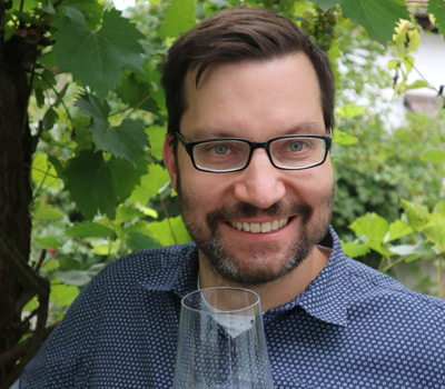Weinliebhaber mit Weinglas im Weinberg lächelnd