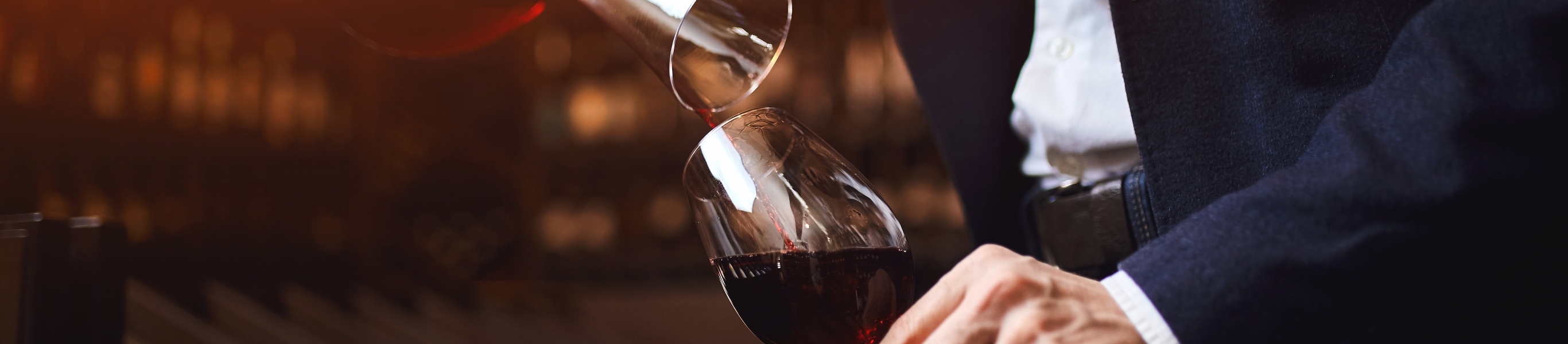 Ein Blätterwald voll Wein: Ausgesuchte Rotweine bei uns! Wein wird in Glas eingeschenkt, edler Genuss, elegant