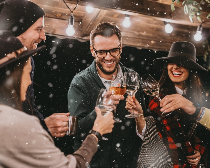 Freunde stoßen mit Wein an, geselliges Beisammensein im Winter