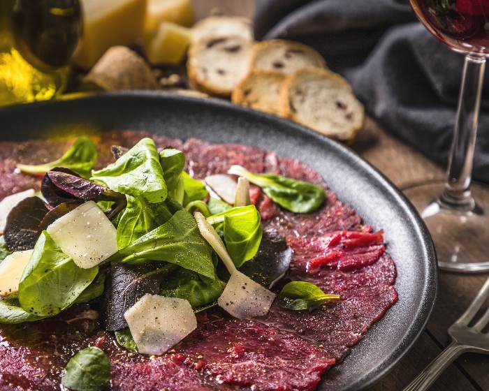 Carpaccio mit Salat, Käse, Brot und Rotwein