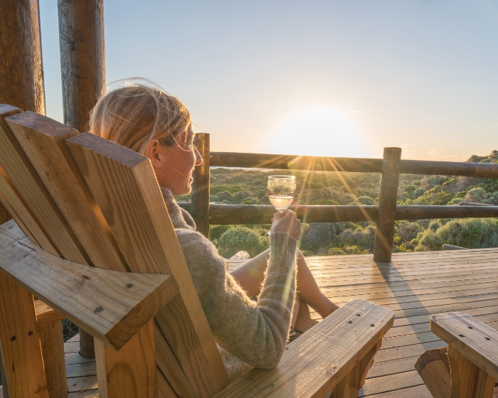 Frau genießt Wein auf Terrasse mit Sonnenuntergang